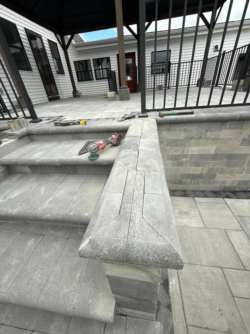 Paved outdoor steps and patio featuring modern stonework with construction tools nearby.